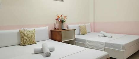 A hotel room with two beds, a small wooden nightstand, and a wall-mounted TV.