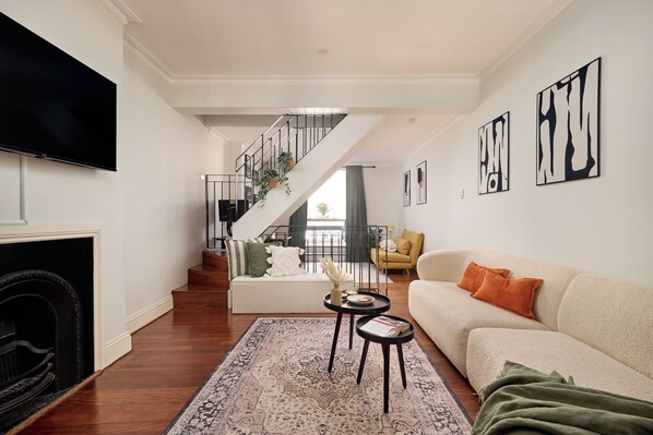 A modern living room with a fireplace, a staircase, a sofa, and a television.