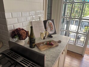 A kitchen counter with a wine bottle, a glass, and a wooden cutting board with strawberries.