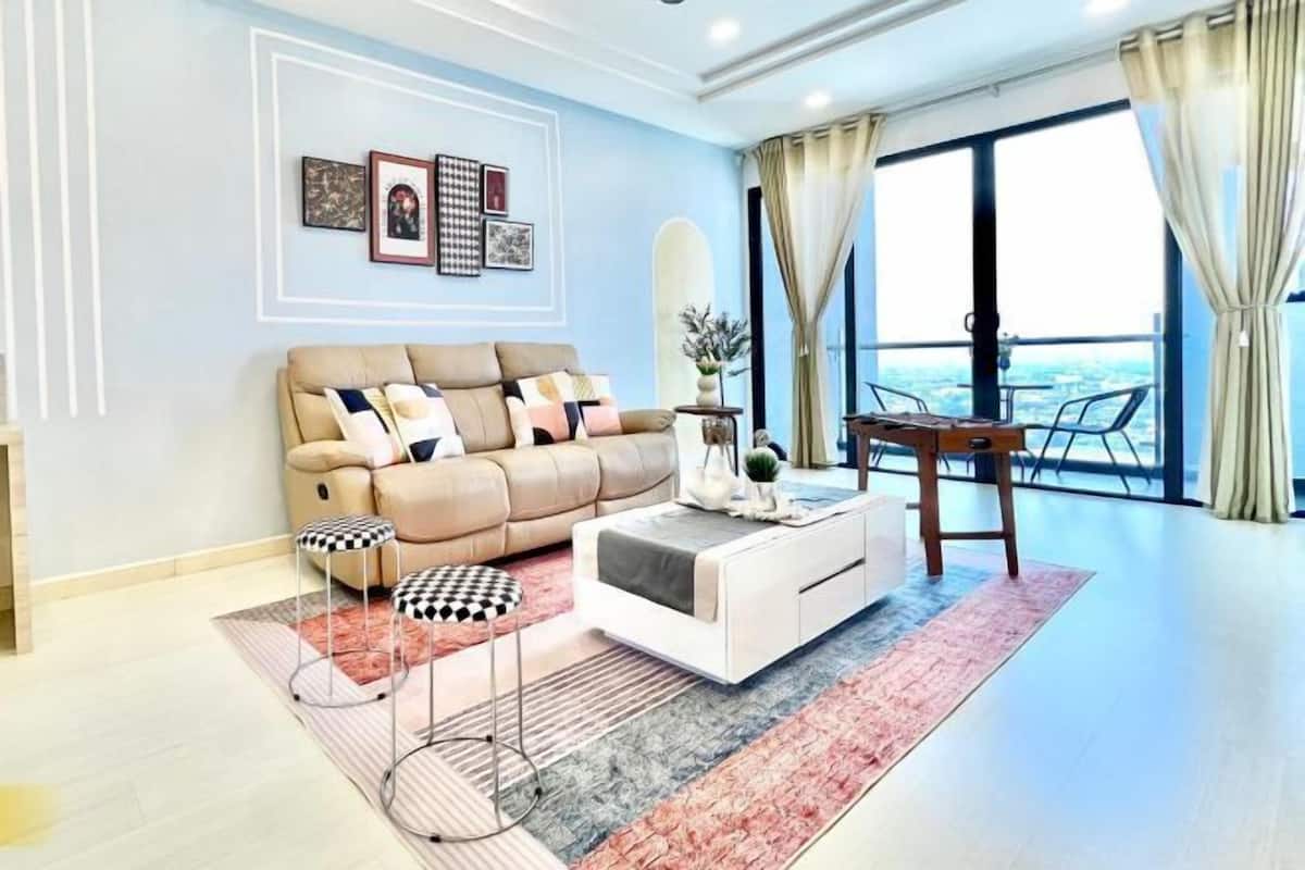 A modern living room with a sofa, coffee table, and a view of the city through large windows.