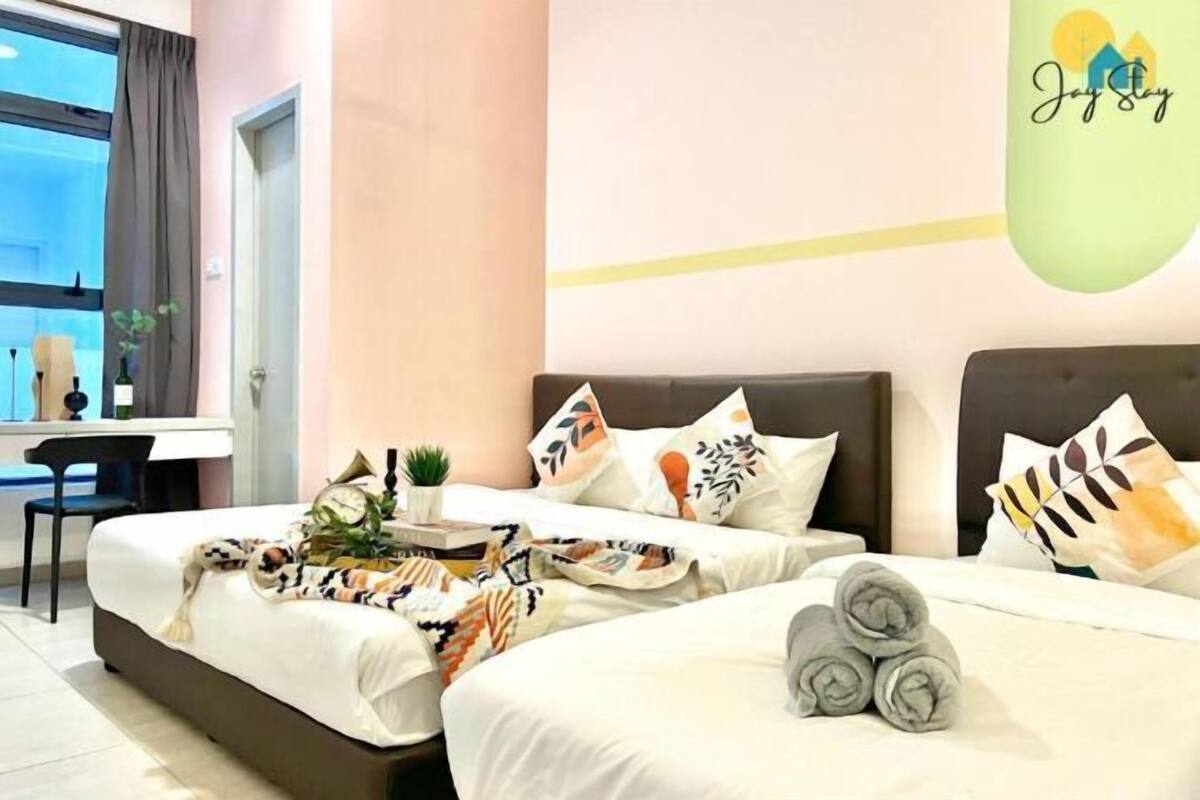A hotel room with two beds, a desk, and a window.