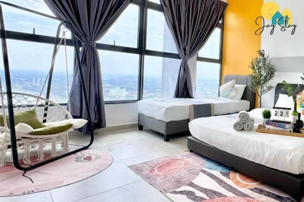 A modern bedroom with a large bed, two smaller beds, a hanging chair, and a view of the city.