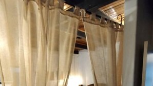 Une chambre à coucher avec un lit, des rideaux, une table de chevet et un plafond en bois.