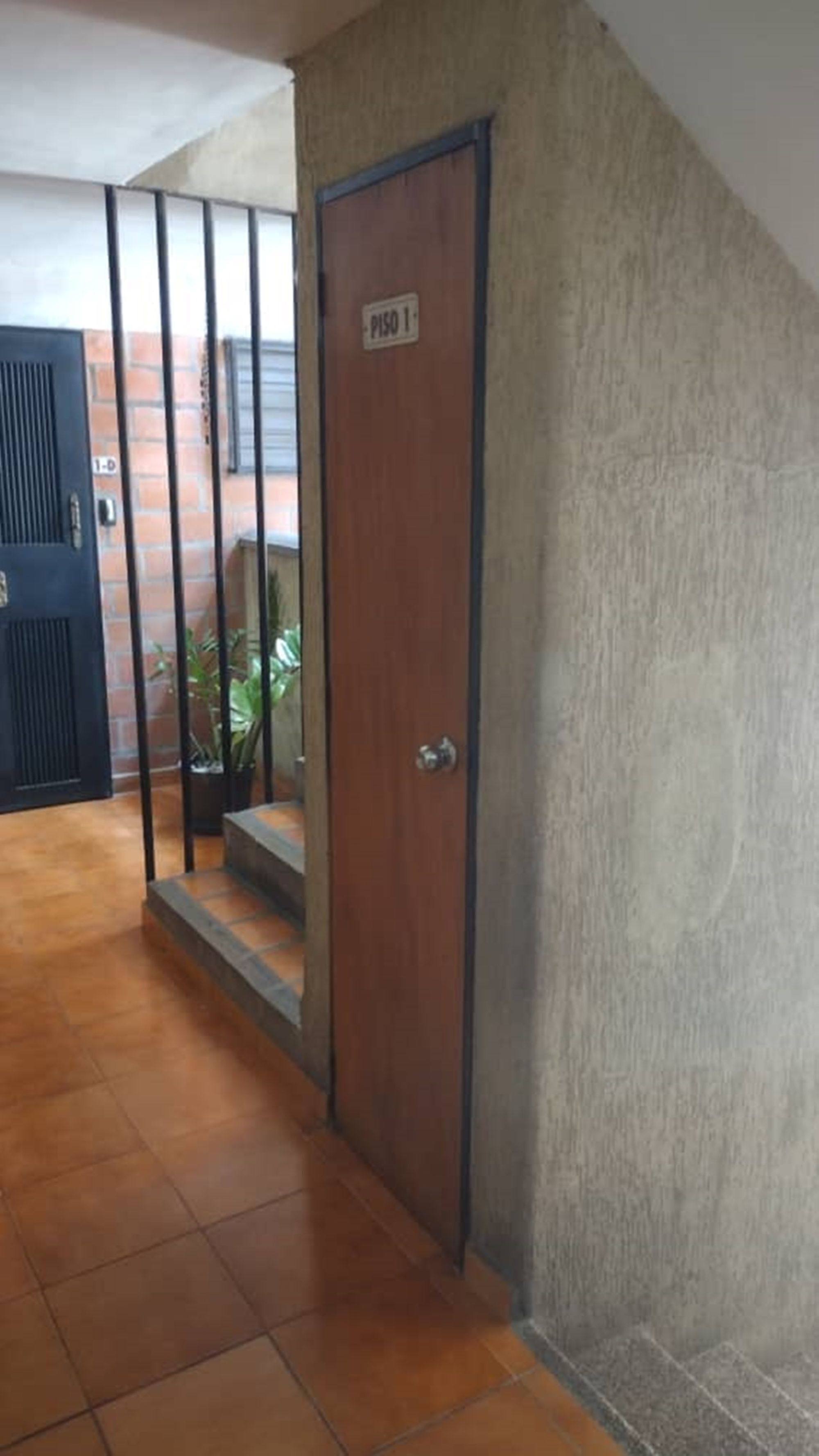 A wooden door with a sign reading "PISO 1" leading to a staircase.