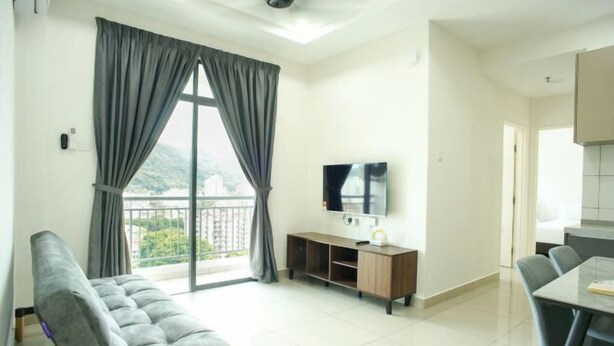 Ein modernes Wohnzimmer mit einer Couch, einem Fernseher und einem Balkon mit Vorhängen.
