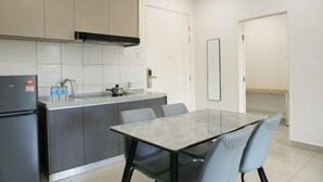 Eine moderne Küche mit grauen Schränken, einem schwarzen Kühlschrank und einem Glastisch mit Stühlen.