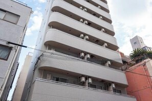 Un edificio de varios pisos con balcones y unidades de aire acondicionado.