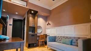 A room with a sofa, a dining table, a chair, a small kitchen area, and a mirror on the wall. - The Palm Suite at Lava Mansion (George Town)