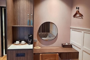A hotel room with a wooden cabinet, a round mirror, a wooden desk, and a hanging coat rack. - The Palm Suite at Lava Mansion (George Town)