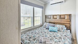 A bedroom with a bed, a window with blinds, an air conditioning unit, and a patterned bedspread. - Twin Cottage Retreat · Poconos Luxury Stay (Pleasant Mount)
