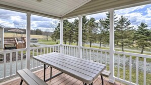 A covered outdoor area with a table and benches, surrounded by a white railing, overlooking a grassy area with trees. - Twin Cottage Retreat · Poconos Luxury Stay (Pleasant Mount)