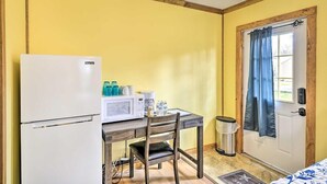 Una stanza compatta con angolo cottura, dotata di frigorifero, forno a microonde e macchina del caffè.