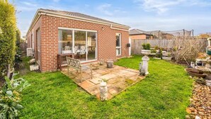 Une maison en briques avec un patio, un jardin et une petite statue.