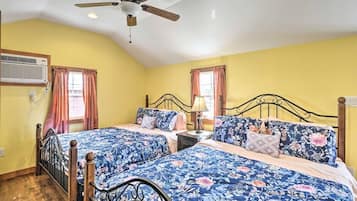A bedroom with two beds, a ceiling fan, and a window with curtains.