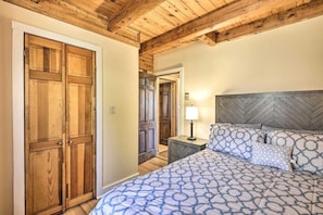 Un dormitorio con cama, armario de madera y mesita de noche con lámpara.