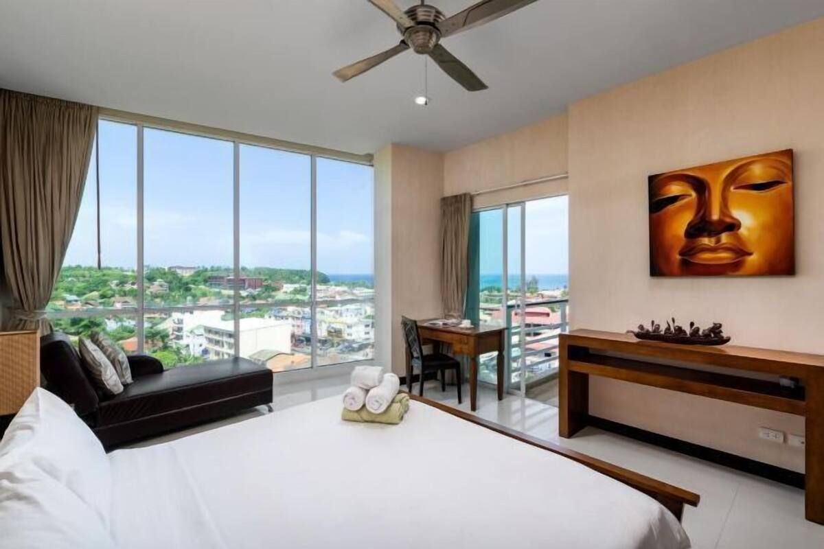 A hotel room with a large bed, a desk, and a view of the city.