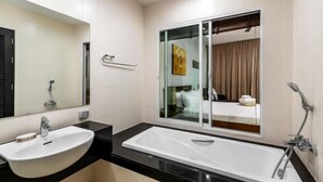 Een moderne badkamer met een groot wit wastafelmeubel, een losstaand bad en een douchecabine met glazen wanden.