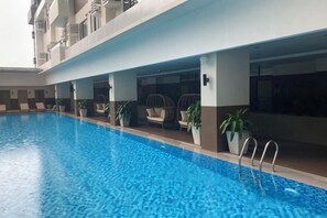 A swimming pool with clear blue water, surrounded by lounge chairs and potted plants. - By Trixia BE Apartments, Luxury Studio Apartments near IT Park (Cebu City)