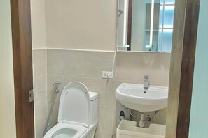 Une salle de bain avec des toilettes, un lavabo et un miroir.