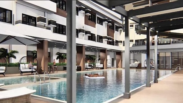 A modern hotel with a rooftop pool, outdoor seating, and a multi-level structure. - By Trixia BE Apartments, Luxury Studio Apartments near IT Park (Cebu City)
