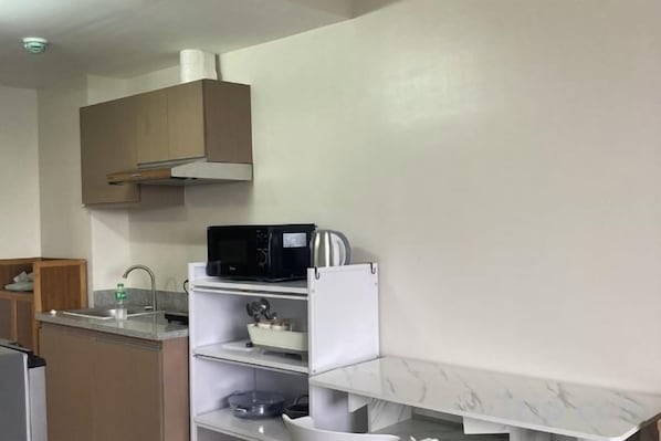Une cuisine équipée d’un four à micro-ondes, d’une bouilloire et d’un meuble blanc.