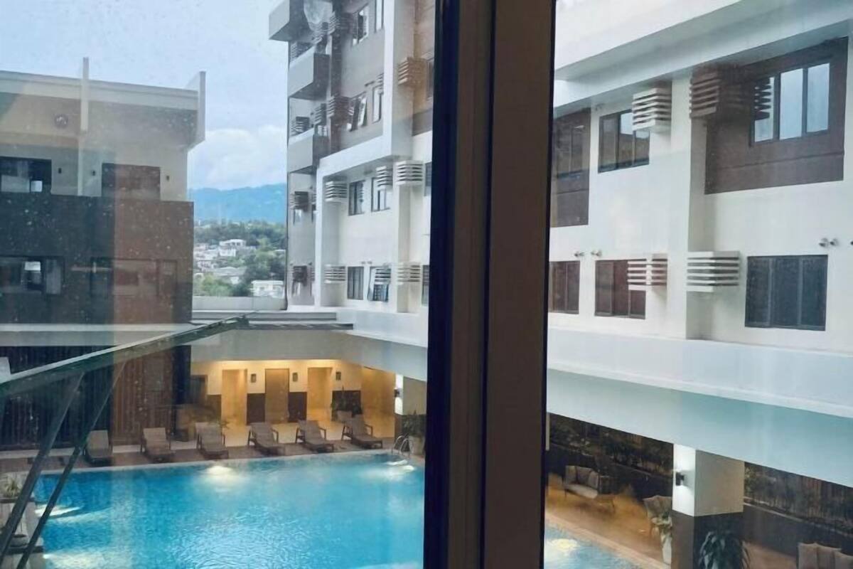 Ein mehrstöckiges Hotel mit einem zentral gelegenen Schwimmbad, Balkonen und Blick auf die Umgebung.