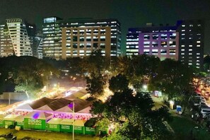Une vue nocturne d’une ville, avec ses bâtiments illuminés et un espace extérieur bien éclairé où sont installées des tentes.