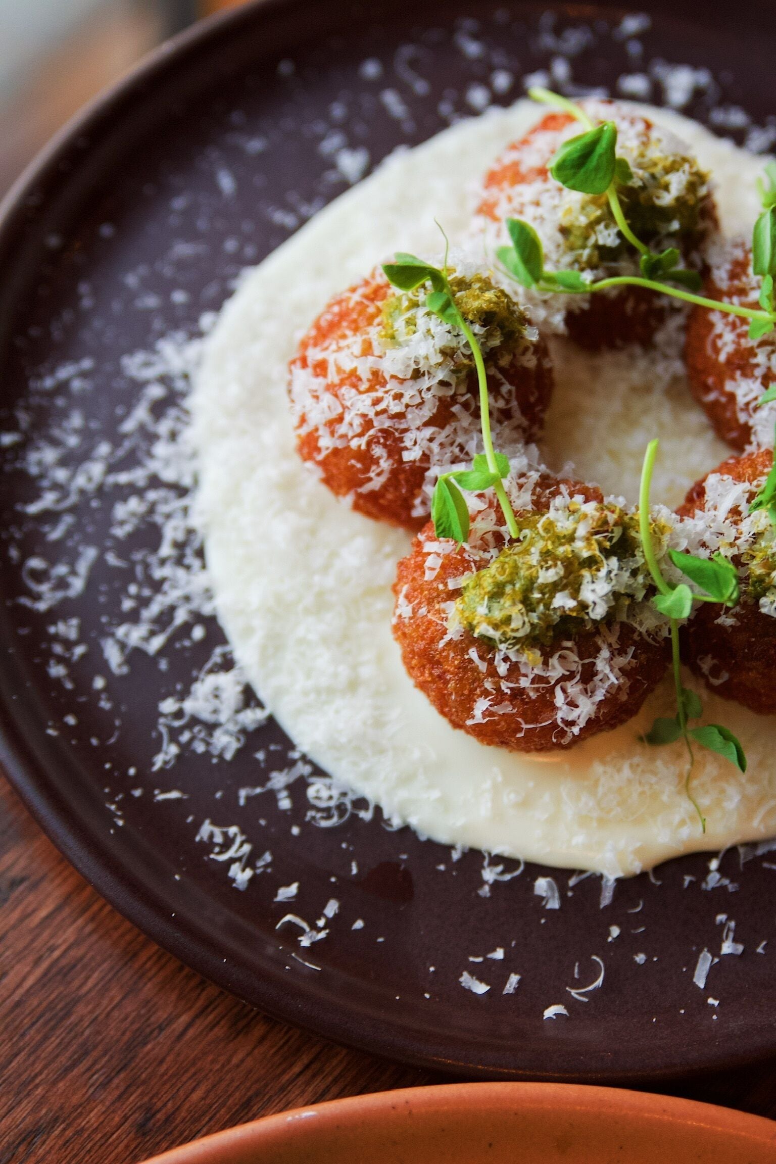 A plate with meatballs, a creamy sauce, and a garnish of green leaves.