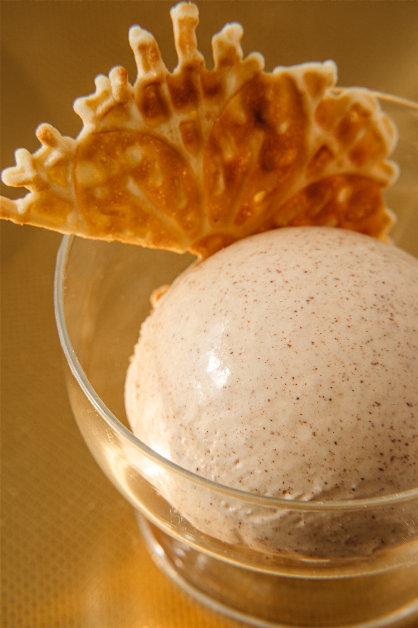 A clear glass bowl containing a dessert with a wafer on top.