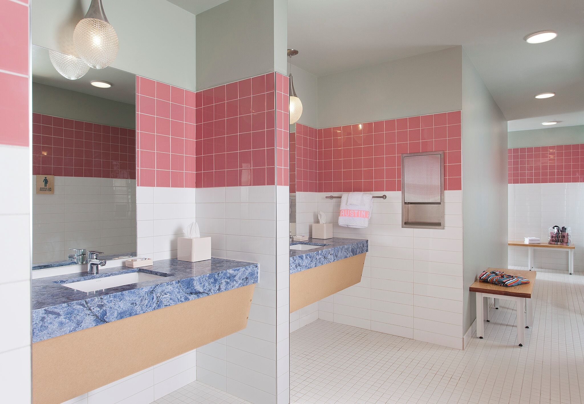 A modern bathroom with a marble countertop, a glass shower enclosure, and pink and white tiles.
