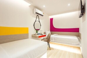 Una habitación de hotel con cama, escritorio, silla, aire acondicionado y televisor.