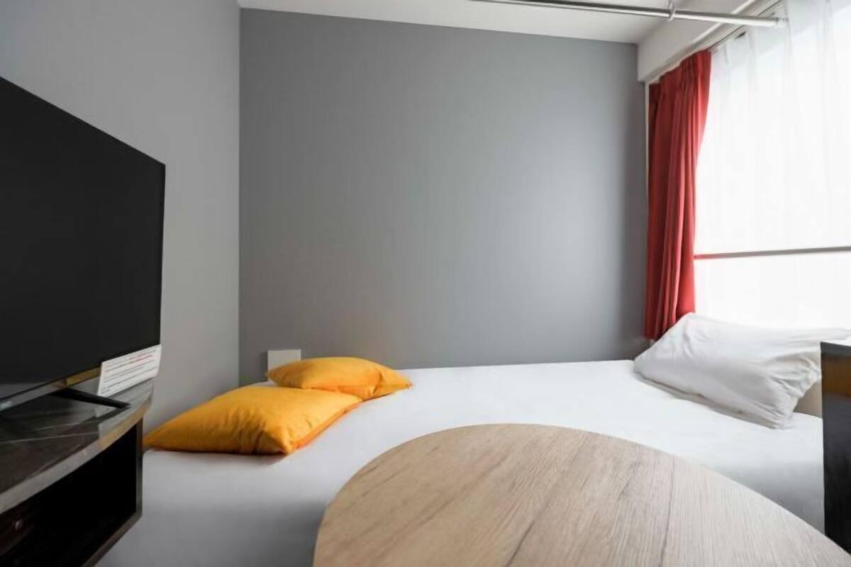 A hotel room with a bed, a TV, and a round wooden table.