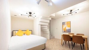 A modern bedroom with a bed, a dining area with chairs, and a staircase. - HJ Place Shibuya (Tokyo)