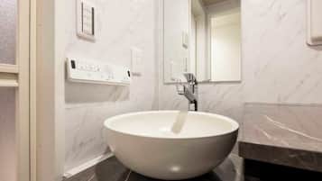 A bathroom with a white vessel sink, a mirror, and a marble wall.