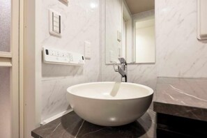 A bathroom with a white vessel sink, a mirror, and a marble wall. - HJ Place Shibuya (Tokyo)