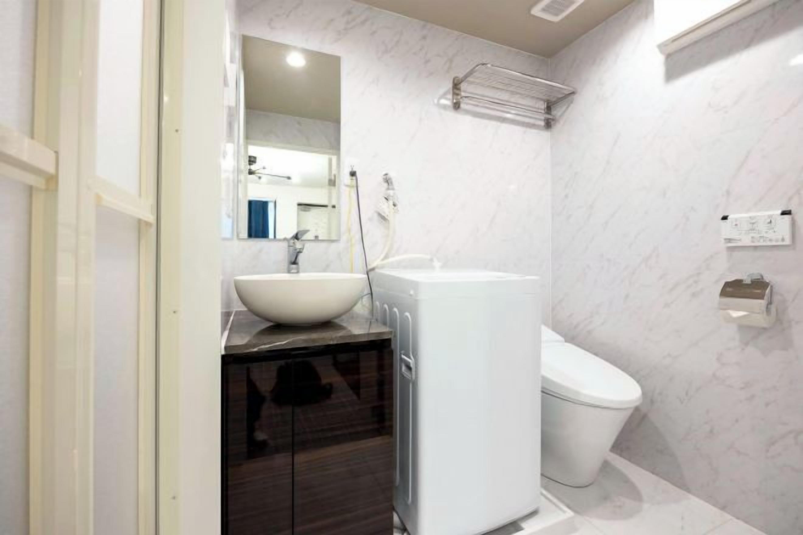 A modern bathroom with a white sink, a white toilet, and a glass shower enclosure.