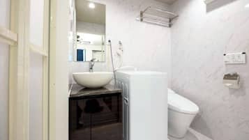 A modern bathroom with a white sink, a white toilet, and a glass shower enclosure.