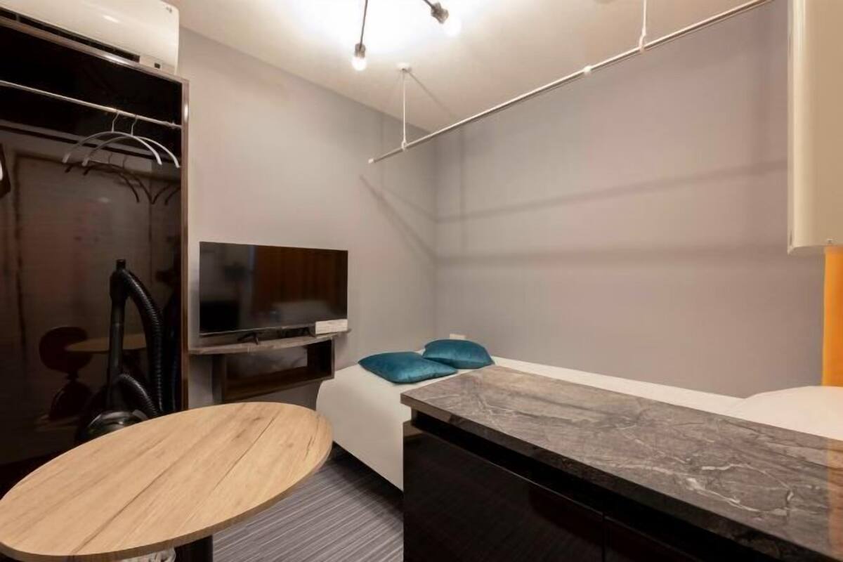 A hotel room with a bed, a TV, a wooden table, and a marble countertop.