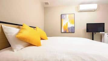 A hotel room with a bed, a flat-screen TV, and a painting on the wall.
