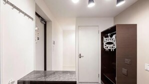 A modern bathroom with a marble vanity, a towel rack, and a walk-in closet with a mirror and shelves. - HJ Place Shibuya (Tokyo)