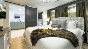 A bedroom with a large bed, a dresser, a mirror, and a view of the outside. - Lodge-style Home Near Gatlinburg w/ Theater, Hot Tub & Game Room Evergreen Escape by Avantstay (Gatlinburg)