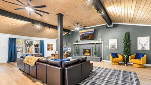 A modern living room with a fireplace, leather sofa, and yellow armchairs. - Lodge-style Home Near Gatlinburg w/ Theater, Hot Tub & Game Room Evergreen Escape by Avantstay (Gatlinburg)