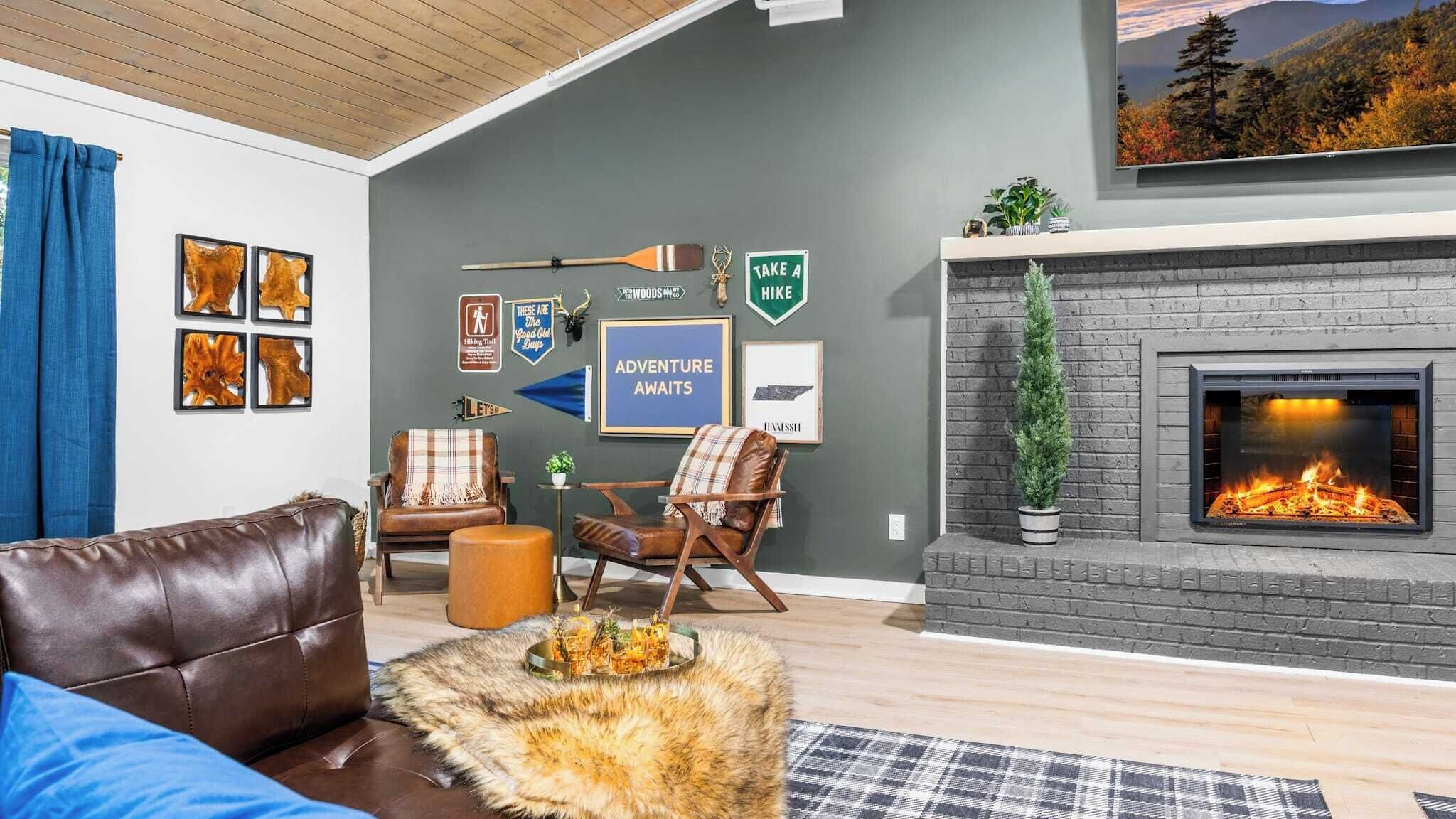 A cozy living room with a fireplace, leather furniture, and various framed signs and posters on the wall.