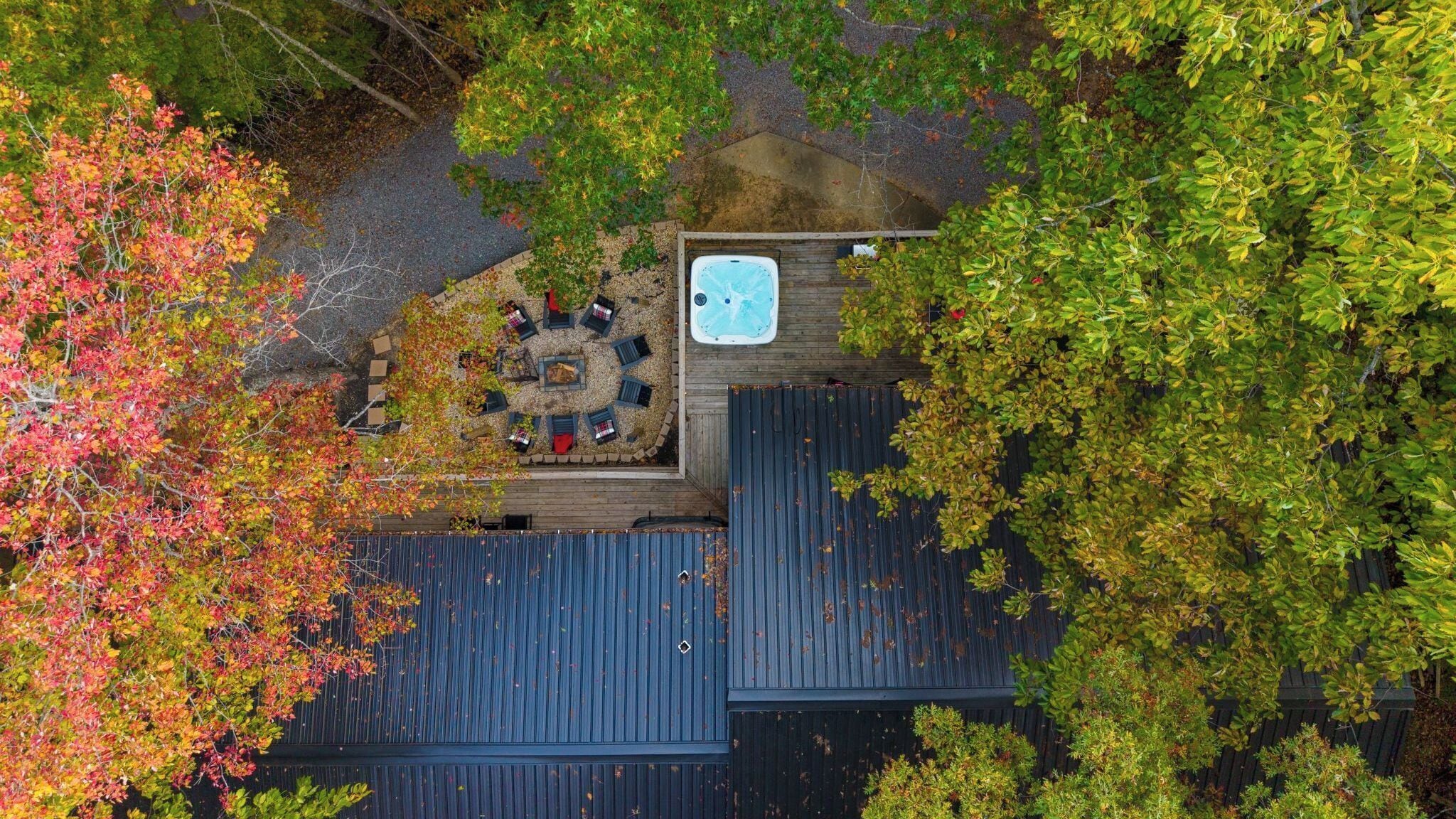 Vista aérea de una azotea con jacuzzi, mobiliario exterior y árboles circundantes.