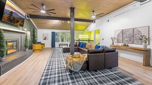 A modern living room with a fireplace, leather sofas, a checkered rug, and a large TV.
