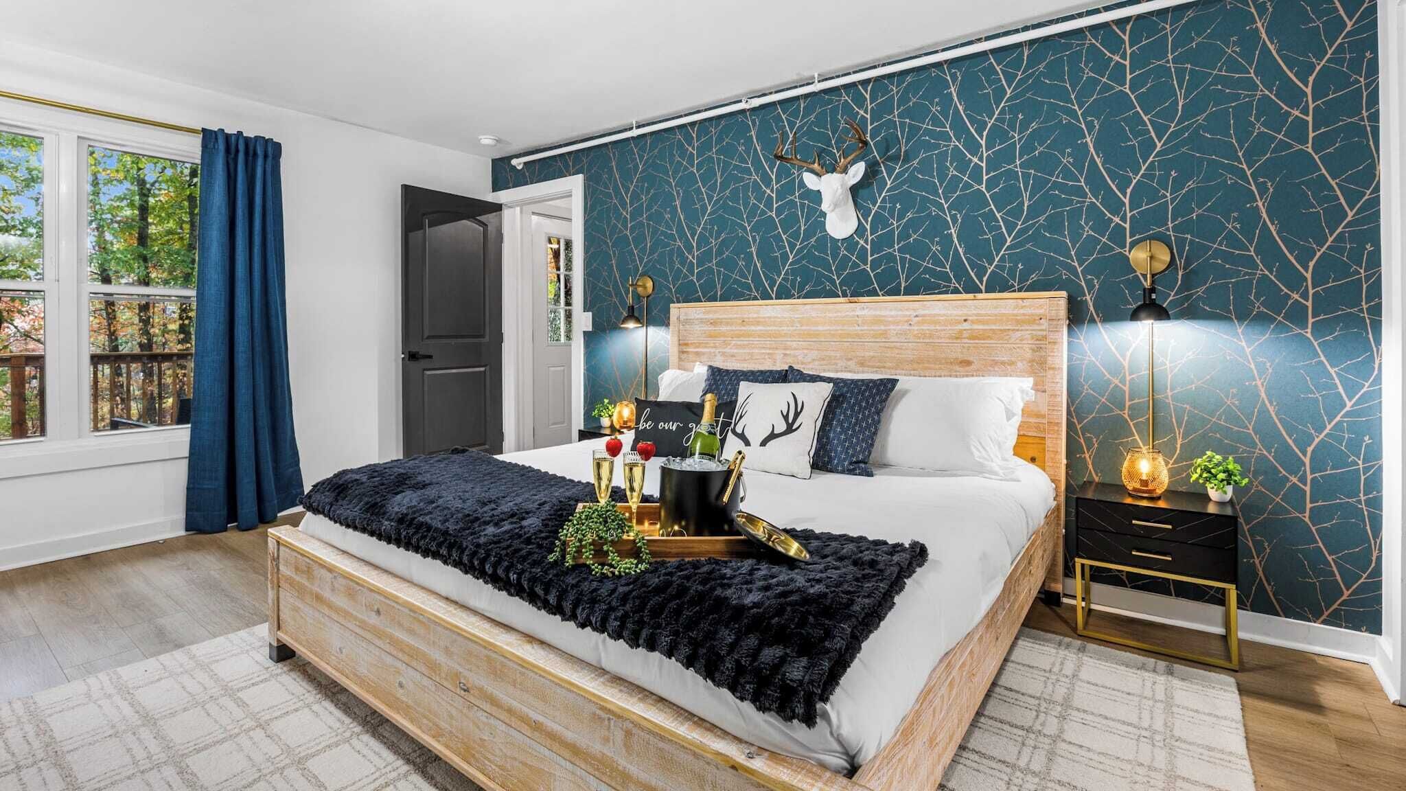 Camera da letto moderna con un letto grande, una testiera in legno, una parete decorata con un motivo color turchese e un ornamento a testa di cervo.