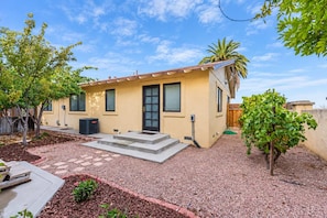 A single-story house with a front porch, a small garden area with mulch, and a palm tree.