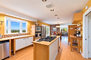 A modern kitchen with a central island, built-in appliances, and a view to the outdoors.