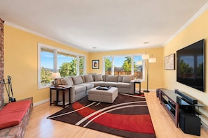 A living room with a sectional sofa, a flat-screen TV, and a fireplace.