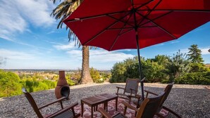 Une terrasse extérieure avec un parasol rouge, une table et deux chaises.